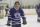 A young man in a blue hockey uniform with a crown logo on an indoor ice rink.